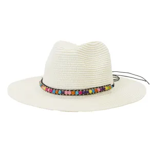 Gros-plan d'un chapeau de paille beige avec bande de perles colorees et detail de cordon noir.