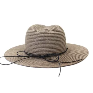 Gros plan sur le chapeau de paille marron avec cordon noir, idéal pour les voyages estivaux.