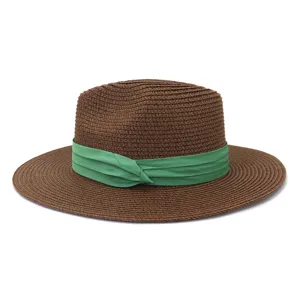 Vue détaillée de la texture du chapeau de paille marron et de son élégant ruban vert.