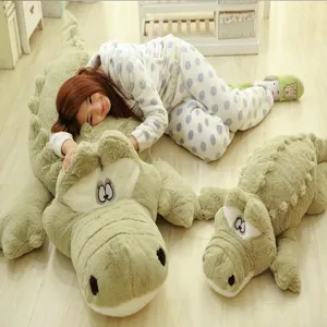 Giant crocodile plush toy and pillow with soft green fur, featuring a cute cozy home scene detail.