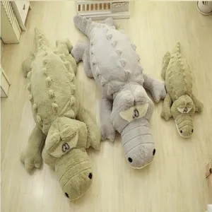 Close-up view of cute soft plush crocodile toys and floor mats on wooden floor.