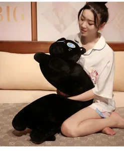 Gros plan de peluche chat noir, oreiller câlin doux dans un cadre de lit confortable.
