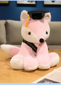 Cute pink plush fox toy wearing graduation cap and ribbon as student graduation gift.