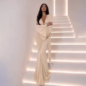 Elegant beige slim-fit maxi dress detail featuring deep V-neck and dramatic long bell sleeves.