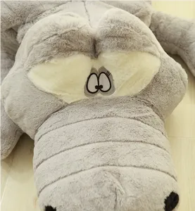 Close-up detail of the giant grey plush crocodile toy, showing soft fabric and cute embroidered eyes.
