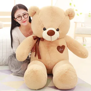 Detailed view of the giant plush teddy bear with brown ribbon bow and heart love patch.