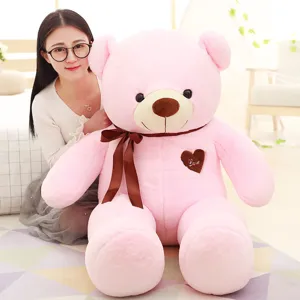 Large cute pink teddy bear plush toy with brown ribbon and heart love patch for sweet gift.