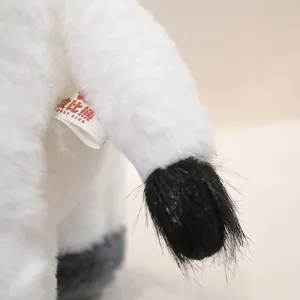 Dettaglio della coda del giocattolo di peluche di mucca con etichetta, morbido e carino.