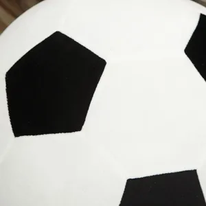 Close-up detail of plush soccer ball toy, soft black and white football pillow for kids.