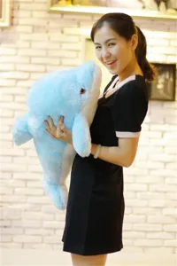 Morbido peluche delfino blu tenuto da un modello, perfetto come cuscino o regalo per bambini.