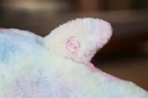 Primo piano dettagliato della pinna in peluche di delfino arcobaleno con logo ricamato.