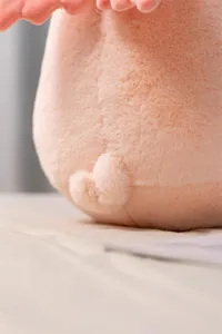 Close-up detail of soft pink angel plush toy with cute tail, premium plush fabric texture.