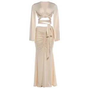 Elegant solid color two-piece outfit with long trumpet sleeve crop top and ruched skirt.