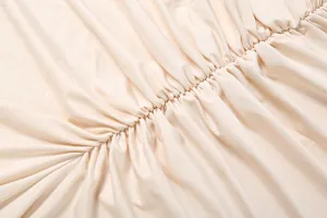 Close-up view of beige pleated fabric detail, showing soft texture and elastic ruching design.