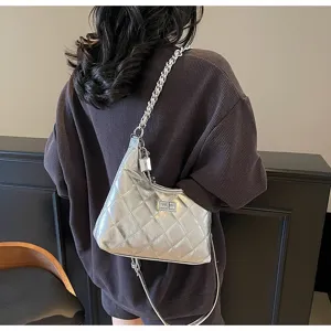 Vue détaillée d'un sac à bandoulière matelassé argenté stylé porté par un modèle.