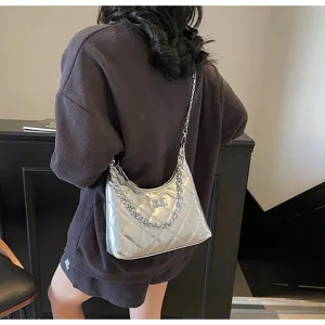 Vue détaillée d'un sac élégant matelassé argenté avec chaîne porté par un mannequin.
