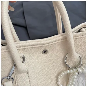 Minimalistische weiße Kunstleder Handtasche Detail, elegante Schultertasche mit Perlenanhänger.