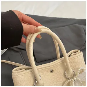 Elegante beige Handtasche aus Leder mit Perlenanhänger, schicke Henkeltasche für Damen.