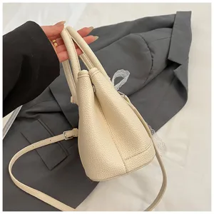 Detailansicht der beigen Handtasche in Lederoptik mit doppelten Henkeln und verstellbarem Gurt.