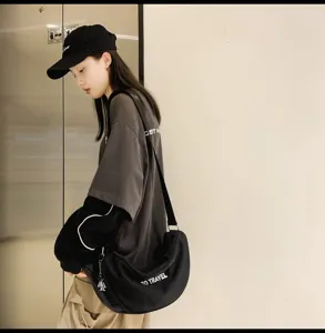 Vista detallada del bolso cruzado negro de lona de estilo japonés informal con estampado de letras.