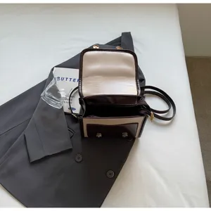 Vista dettagliata di una chic mini borsa a tracolla bicolore con patta aperta e metallo.