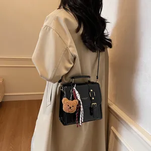Elegante borsa a tracolla nera in pelle da donna con ciondolo orsetto, stile.