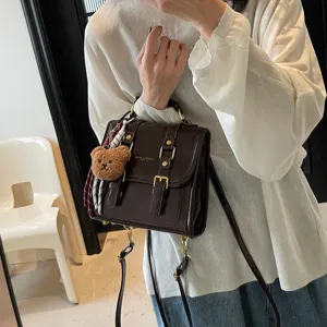 Zaino da donna marrone scuro in vernice stile college con ciondolo orsetto e fibbie.