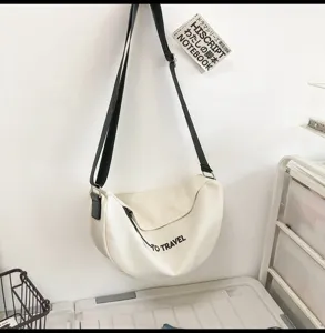 Bolso bandolera informal de lona blanca con correa negra y estampado para uso diario.
