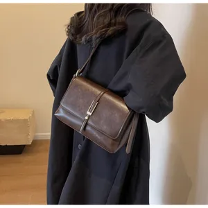 Detailed view of retro dark brown leather underarm shoulder bag with metal clasp.