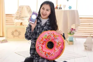 Detailed shot of soft plush donut cushion pillow with colorful sprinkles in cozy indoor room.