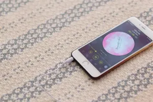Detailed view of smartphone and wired earphone on textured fabric surface lifestyle shot.