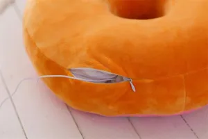 Close-up detail of soft orange donut cushion pillow with zipper, comfortable nap plush toy.