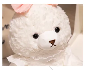 Primer plano detallado de lindo peluche animal blanco con lazo rosa y cuello de encaje.