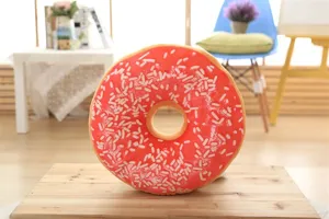 Soft plush donut pillow with pink icing and colorful sprinkles for cozy home decor and nap.
