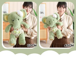 Cute green elephant plush toy with floral pants and hat, soft stuffed animal doll for kids.