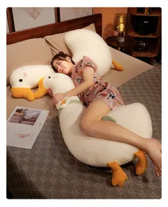 Detalle de peluche de ganso blanco grande con textura suave y almohada de cama acogedora.