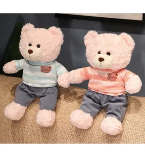 Close-up detail of cute twin plush teddy bears wearing striped sweaters and gray pants.