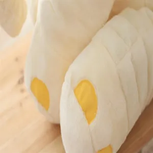 Close-up detail of cute elephant plush toy soothing pillow, soft cream fabric with yellow paws.