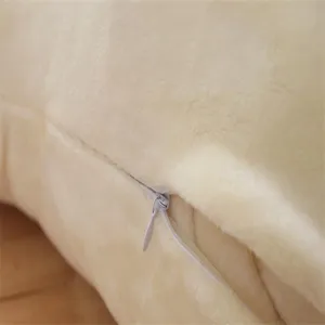 Detailed view of cream plush toy zipper, soft fuzzy fabric cushion cover texture.