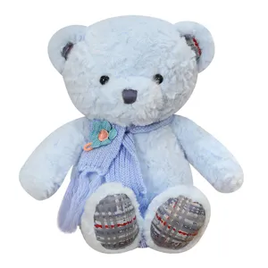 Cute blue plush teddy bear doll with knitted scarf and flower decor, soft hugging pillow.