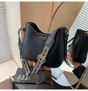 Detailed view of the Korean style black bucket bag with wide strap and hardware in mirror.