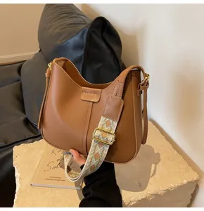 Detailed view of trendy brown bucket bag with wide patterned strap, stylish spring design.