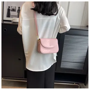 Detail view of a stylish pink crossbody shoulder bag with minimalist design and gold hardware.