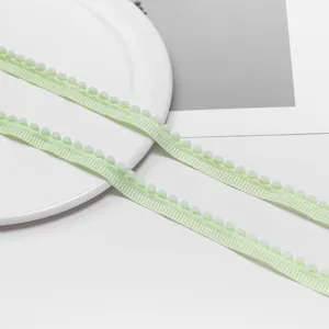 Close-up detail of light green pom-pom trim ribbon for DIY crafts and sewing projects.