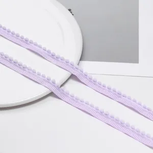 Detailed close-up shot of light purple pom pom fringe trim, perfect for DIY crafts and sewing.