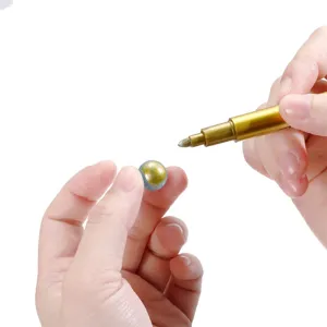 Detailed shot of a metallic marker pen being used to paint a small round bead, clear.