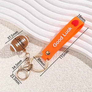 Mini football keychain with orange Good Luck strap and metal hooks for sports fans.