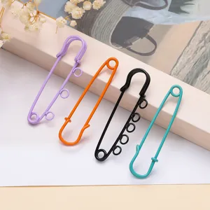 Detailed view of colorful baked paint 3-hole and 5-hole large safety pins for DIY craft.