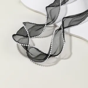 Close-up detail of black sheer organza ribbon with delicate white pearl beaded edge.