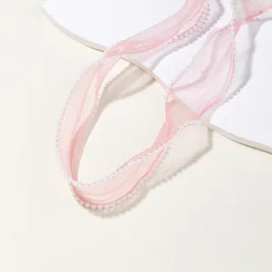 Close-up detail of pink pearl-edged organza ribbon, delicate trim for DIY crafts and decor.